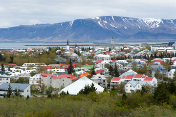 Fototapeta premium Aerial view of downtown rooftops seen during a grey cloudy day, with sea and mountains in the background, Reykjavik, Iceland