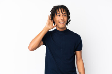 Fototapeta premium Young african american man isolated on white background listening to something by putting hand on the ear