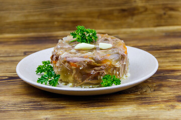 Meat aspic in a plate on a wooden table. Traditional russian dish