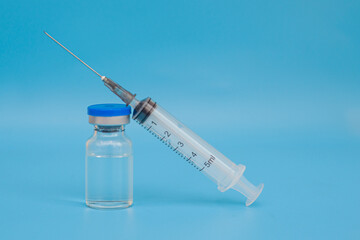 Ampoule with medicine or vaccine and syringe on blue background