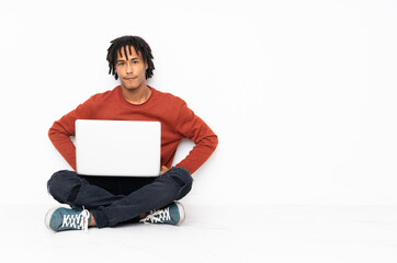 Young african american man sitting on the floor and working with his laptop angry