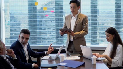 asian business man holding tablet and presentation in Meeting at office on window . manager man standing and present . Financial Teamwork discussing strategy at workspace on cityscape - Powered by Adobe