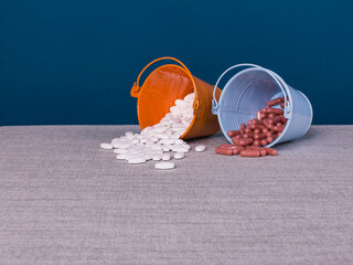 Two small buckets with different pills. The concept of choosing an alternative to medical treatment.