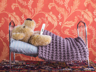 Lockdown, sick teddy bear lies at home alone in bed.