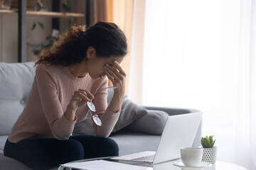 Exhausted millennial caucasian woman taking off eyeglasses, suffering from dry eyes syndrome from...