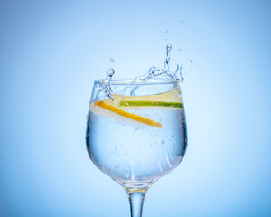 glass of water with lemon droped in and splash