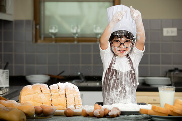 Happy cute asian  little boy in apron preparing baking the dough in kitchen room at home