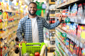Happy African American Guy Posing In Supermarket, Smiling To Camera