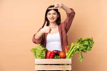 Young farmer girl with freshly picked vegetables in a box focusing face. Framing symbol