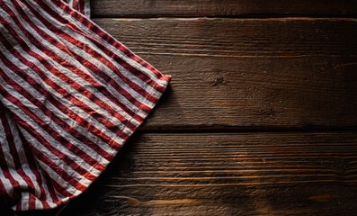 a towel made of red and white striped fabric, lying on a table made of wood with a texture, daylight falls from the window. copy space