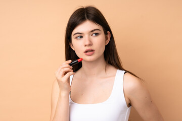 Fototapeta premium Young Ukrainian teenager girl over isolated background holding red lipstick