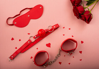 BDSM set of red color and a bouquet of roses on a pink background. Love symbol for valentine's day.