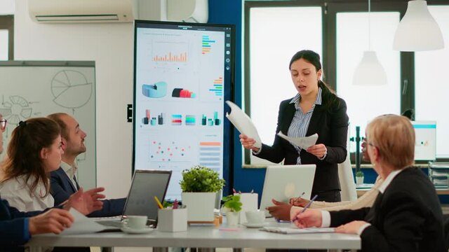 Angry business woman screaming at diverse colleagues during office meeting throwing away documents, disagreeing about bad business contract. Young multiracial group of people working in boardroom.