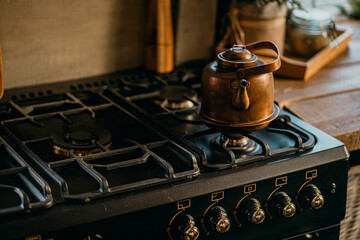 Old stylish kitchen in the apartment, sunny daylight from the window. copy space. a red towel. a copper metal teapot sits on a gas stove vintage