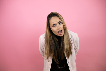 Fototapeta premium Young beautiful blonde woman with long hair standing over pink background afraid and shocked with surprise and amazed expression, fear and excited face.
