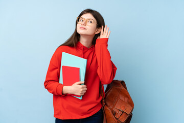Obraz premium Young Ukrainian teenager student girl holding a salad over isolated blue background listening something