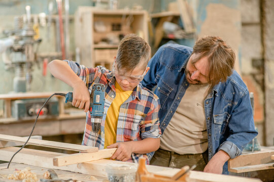 Father teaches son carpentry at a workshop