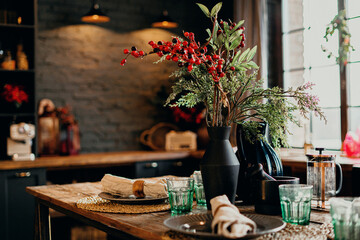 vintage serving on a wooden table, beautiful dishes made of glass in different colors. Flowers on the table in the center