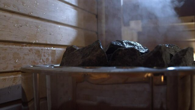 Pouring water into hot stone in sauna in HD