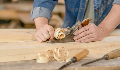 Close up carpenter's hands planed wood in a workshop