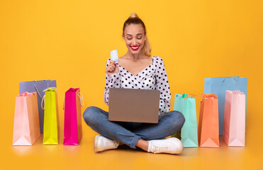 Happy woman with shopping bags, laptop and plastic card