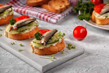 Smoked sprat sandwich - fish, fresh cucumber and tomato. Sprat sandwiches on toasted slices of bread