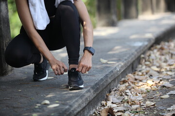 Runner getting ready for jogging tying running shoes laces - Woman preparing before run putting on trainers in  park ,Photo of attractive woman in fashionable sportswear. Dynamic movement. Sport
