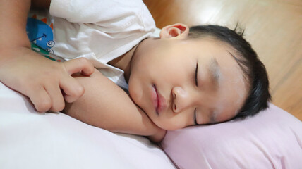 Fototapeta na wymiar Asian little cute boy sleeping in white bed and pilow. 2 years old.