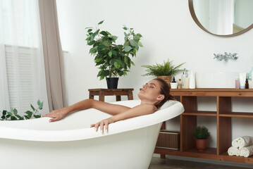 A pretty brunette lies in the bath and relaxes. The concept of skin care and relaxation