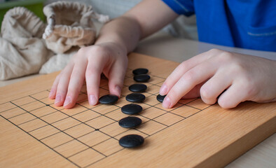 child plays the go game. Bag, board and stones close up