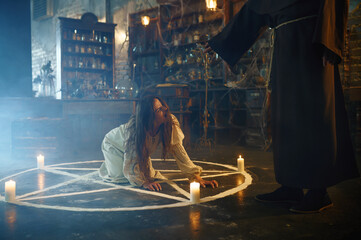 Exorcist in hood casting out devil from a woman