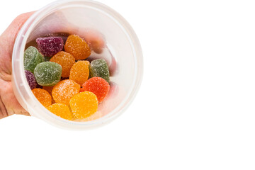 Close up view of hand holding plastic jar with colorful marmalade gummies.