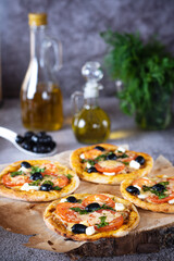 pizza lies on a wooden board on a dark table next to olive oil and herbs. The process of making homemade pizza.