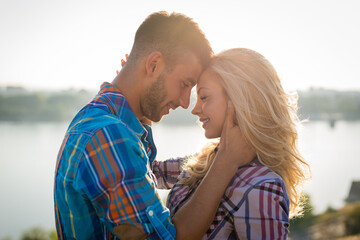 Emotional romantic couple in love smiling and enjoying beautiful day in nature at the beach. Young lovers touching