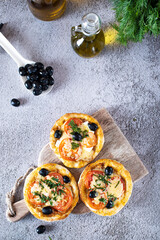 pizza lies on a wooden board on a dark table next to olive oil and herbs. The process of making homemade pizza.