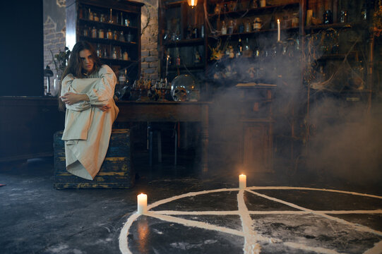 Young demonic woman sitting near magic circle