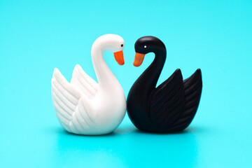 Two toy swans black and white on a blue background
