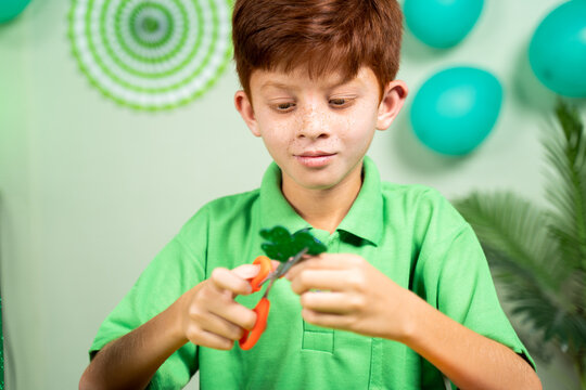 Young Kid Busy In Preparing Shamrock Leaves For Saint Patricks Day Festival Celebrations At Home.