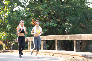 asian athletics couple woman jogging and exercising together in public park in the evening