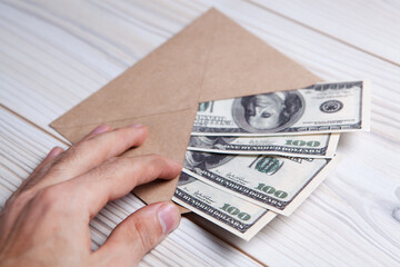 US dollars in an envelope on a wooden table. Income, bonuses or bribes concept.