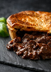 British beef steak pie with onion, wine gravy on rustic stone board
