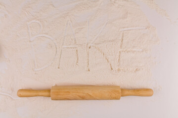 word baked goods on white background flour with rolling pin on kitchen table