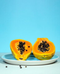 Two Half of Papaya with Green and Seeds on Blue Background, Minimalism Trendy Food, Healthy and Detox Eating, Raw lunch, Vertical Copyspace, Exotic Fruit