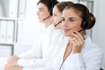 Call center. Beautiful young woman using headset and computer to help customers. Business concept