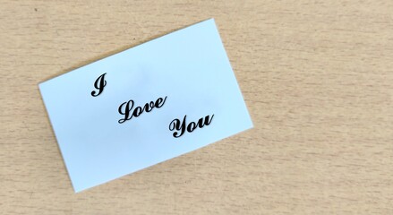 I love you text word written on a paper peace, wooden background, Valentine's Day greetings