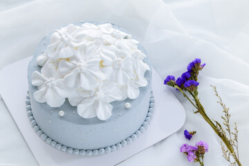 Pastel blue coconut cake decorated with white flowers from fresh cream