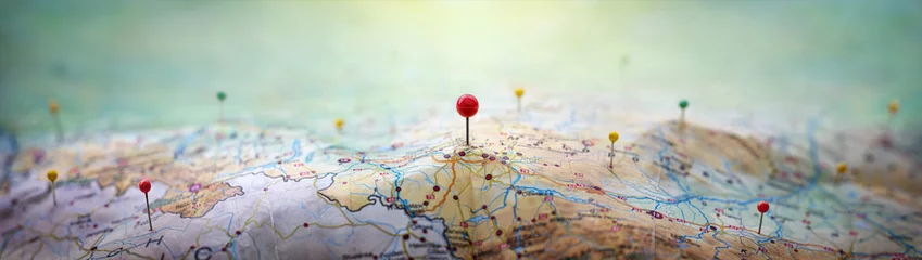 Fotobehang Pins on a geographic map curved like mountains. Pinning a location on a map with mountains. Adventure,  geography, mountaineering, hike and travel concept background. © Tryfonov