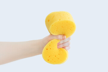 Yellow foam sponge washcloth clenched in the hand of Caucasian woman.