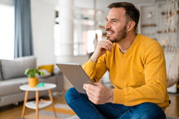 Happy man relaxing on sofa with digital tablet