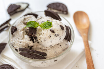 Chocolate cookie and ice cream in a glass bowl with mint leaf on white wooden background, summer...